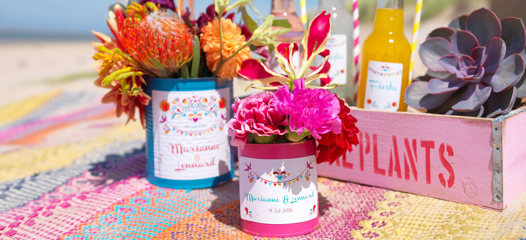Bunte Töpfe mit Blumen und Getränken auf einem bunten Tuch.