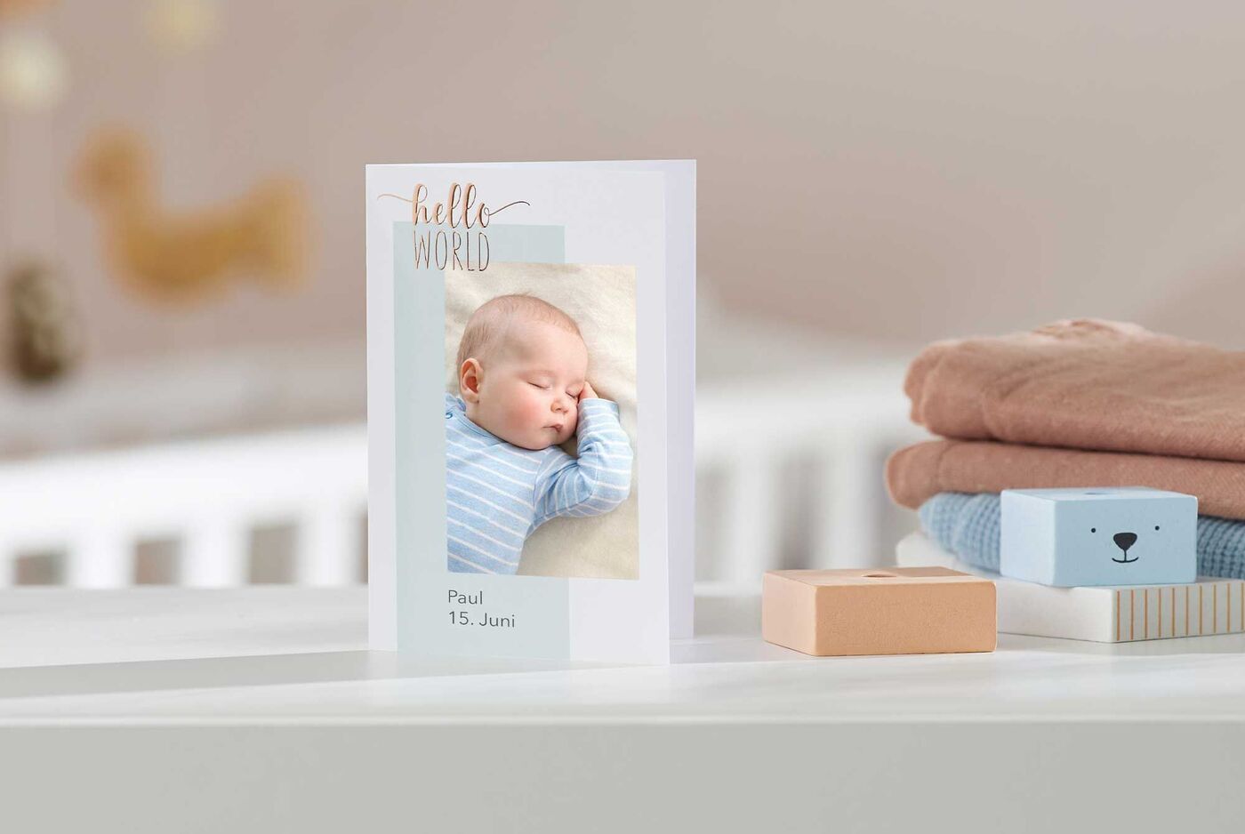 Eine liebevolle Grußkarte mit einem Babyfoto, auf der steht 'Hello World' und dem Namen Paul mit dem Datum 15. Juni