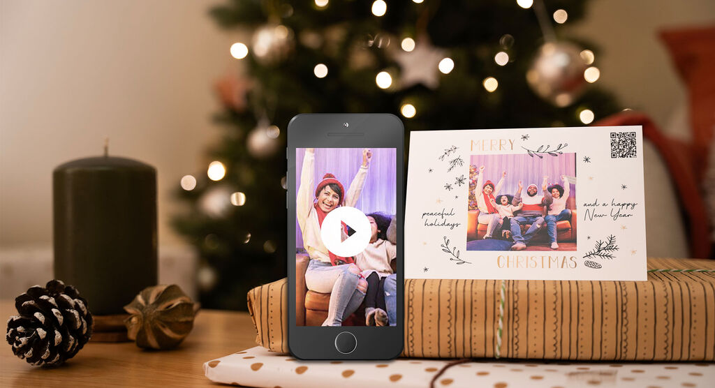 Frohe Weihnachten: Freude mit Freunden vor einem Weihnachtsbaum, eine Karte und ein Handy mit Video.