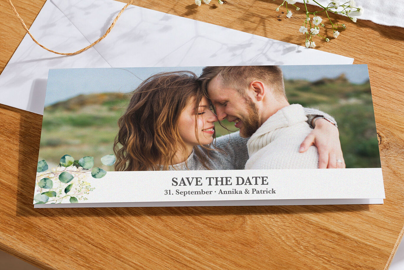 Paar hält sich liebevoll umarmt bei einem Save-the-Date Foto, umgeben von einer blühenden Naturkulisse