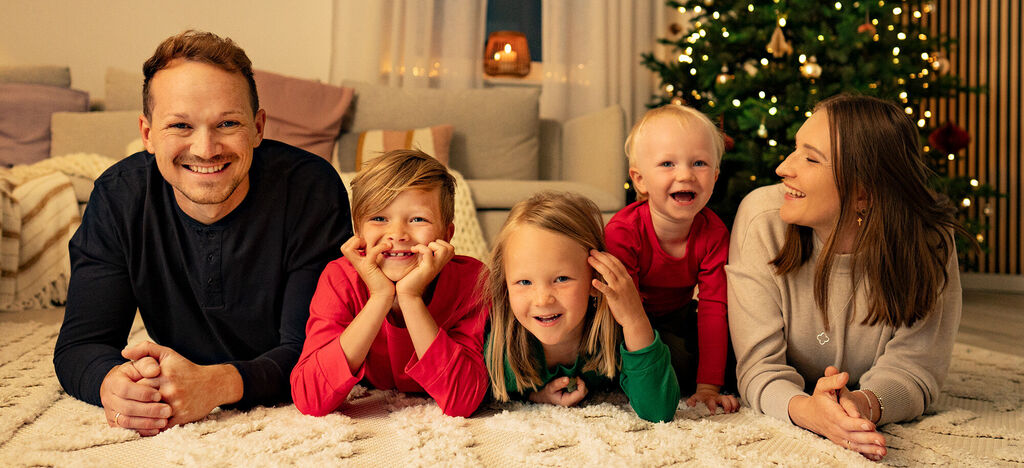 Familie entspannt glücklich am Weihnachtsabend auf dem Teppich vor dem Weihnachtsbaum