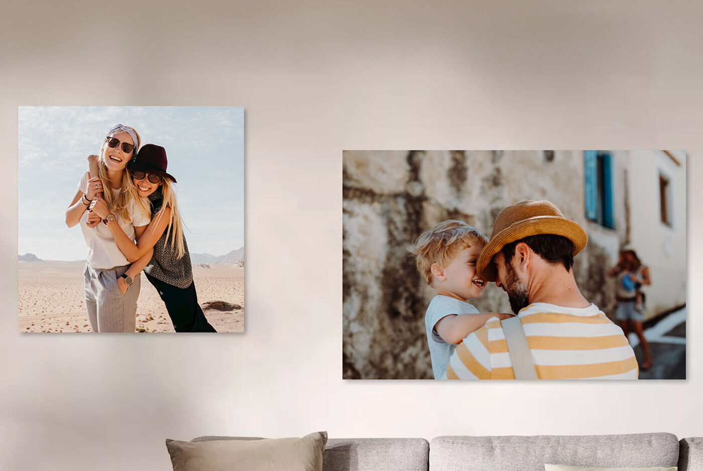 Zwei CEWE Wandbilder auf einer Wand, das linke zeigt eine Frau mit Kind im Freien und das rechte einen Vater mit Kind, beide strahlen Freude aus