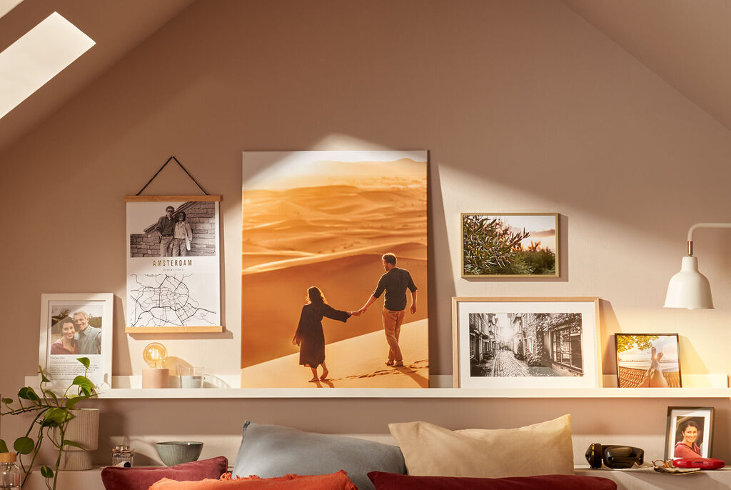 Zwei Personen gehen Hand in Hand über eine Sanddüne, umgeben von inspirierenden Fotografien an der Wand
