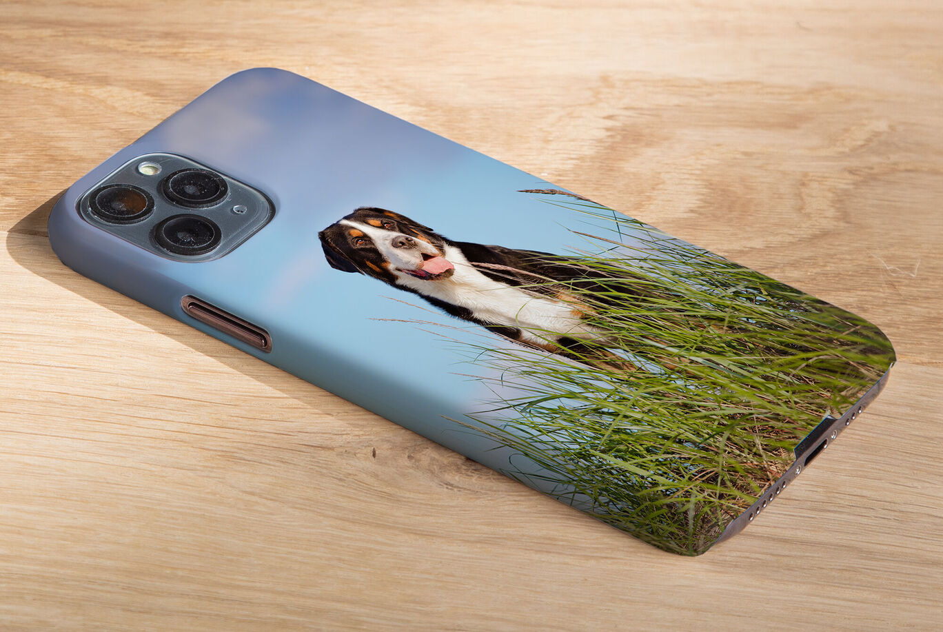 Handy mit personalisiertem Hüllenmotiv eines Hundes im Gras.