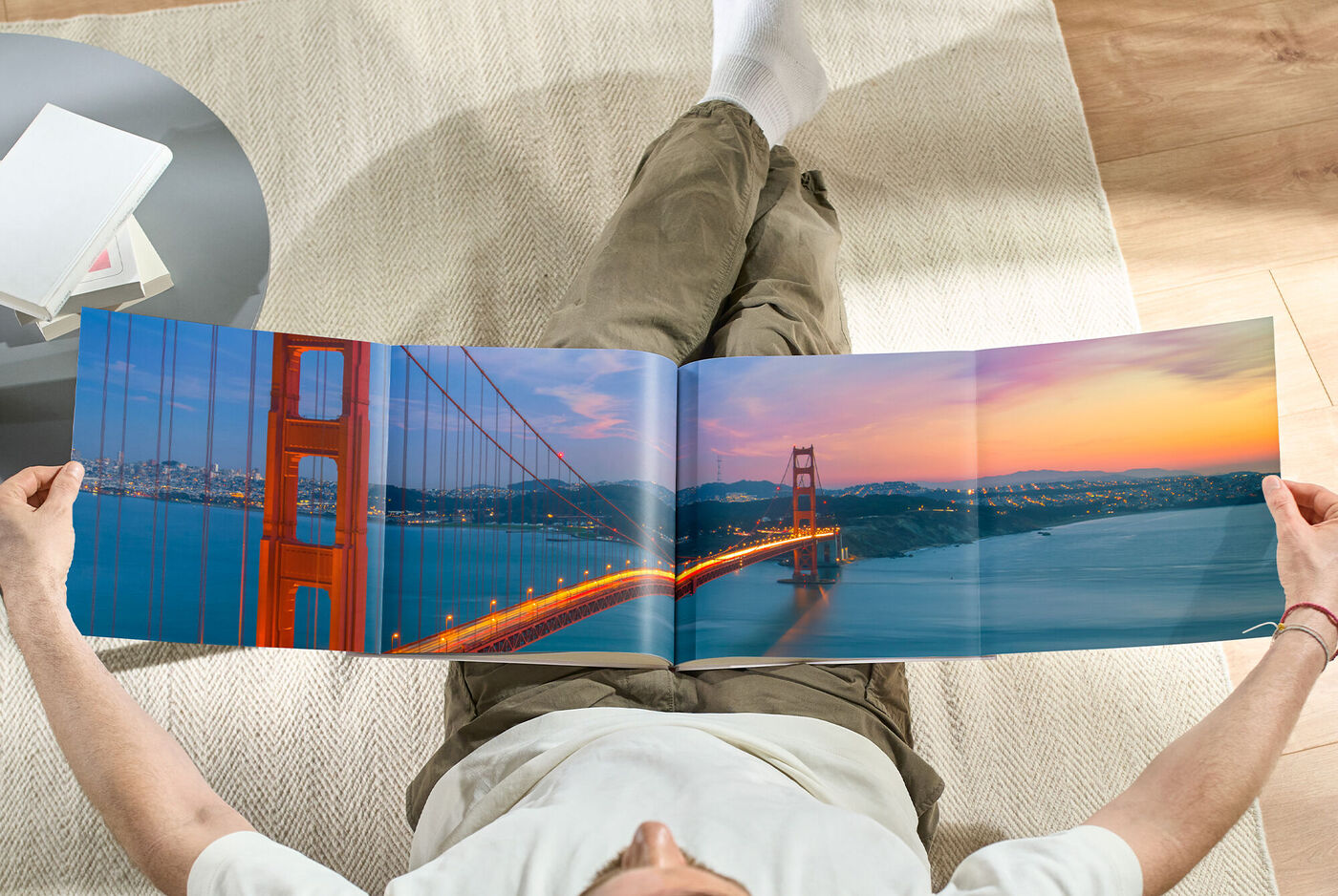 Eine Person betrachtet ein weit geöffnetes Fotobuch mit einem Bild der Golden Gate Bridge bei Sonnenuntergang.