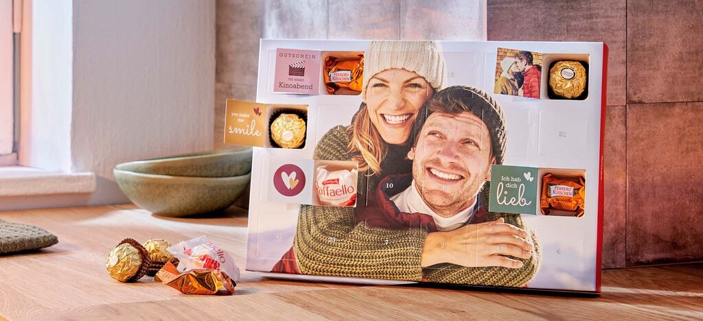 CEWE Adventskalender gefüllt mit Pralinen von Ferrero und persönlichen Botschaften in den Türchen mit dem Foto eines glücklichen Paares.
