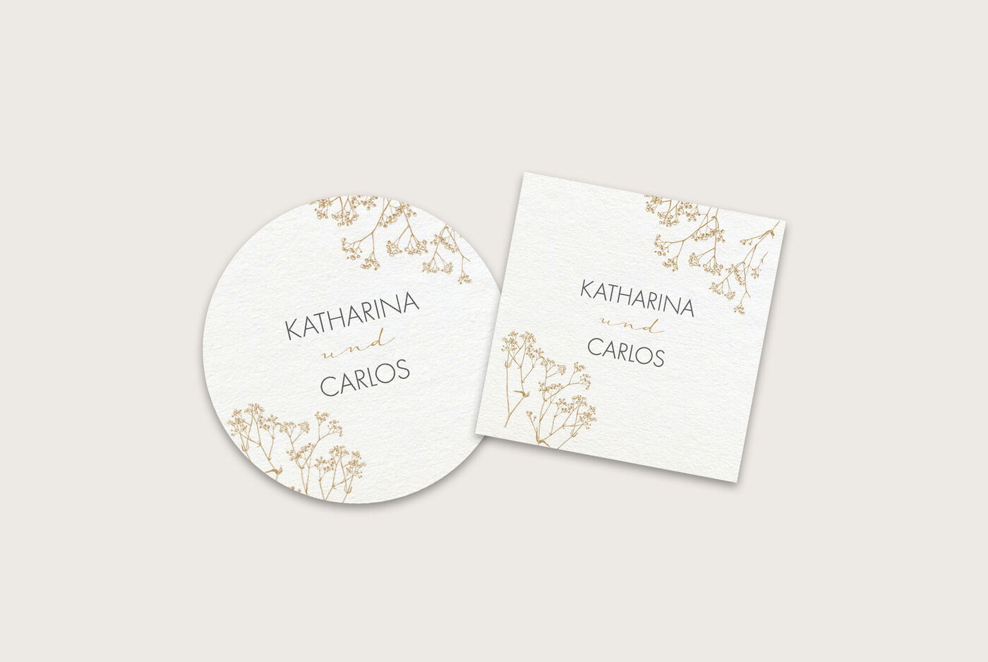 Zwei elegante Einladungskarten mit goldenen Verzierungen und den Namen Katharina und Carlos