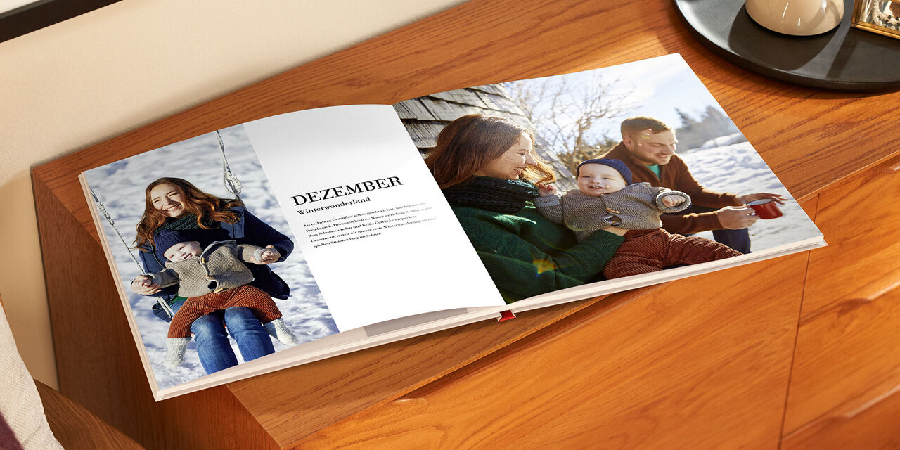 Eine liebevolle Familienszene im Winter mit einem geöffneten Fotobuch.