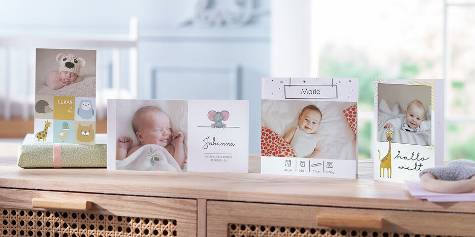 Fünf liebevoll gestaltete CEWE Grußkarten mit Babyfotos in einem hellen Raum.