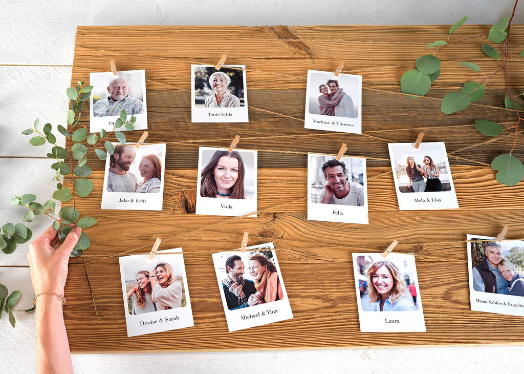 Eine rustikale Wand mit zahlreichen Fotos, die an einer Holzlatte befestigt sind, strahlt ein Gefühl von Verbundenheit und Freude aus. Die Bilder zeigen lächelnde Menschen und schöne Erinnerungen.
