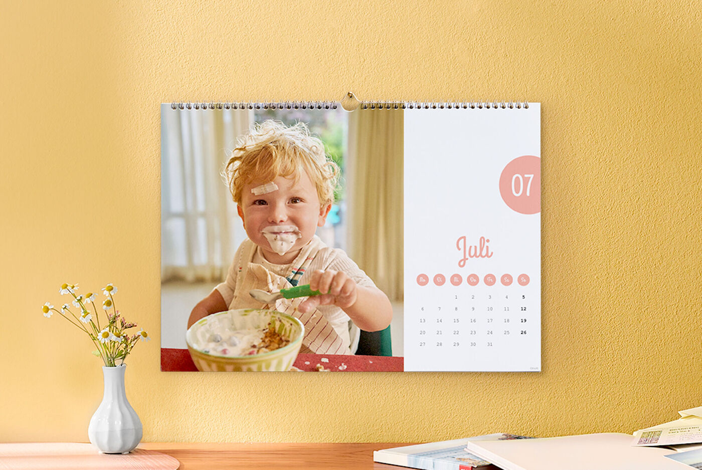 Ein CEWE Fotokalender mit einem fröhlichen Kind, das einen Löffel hält.