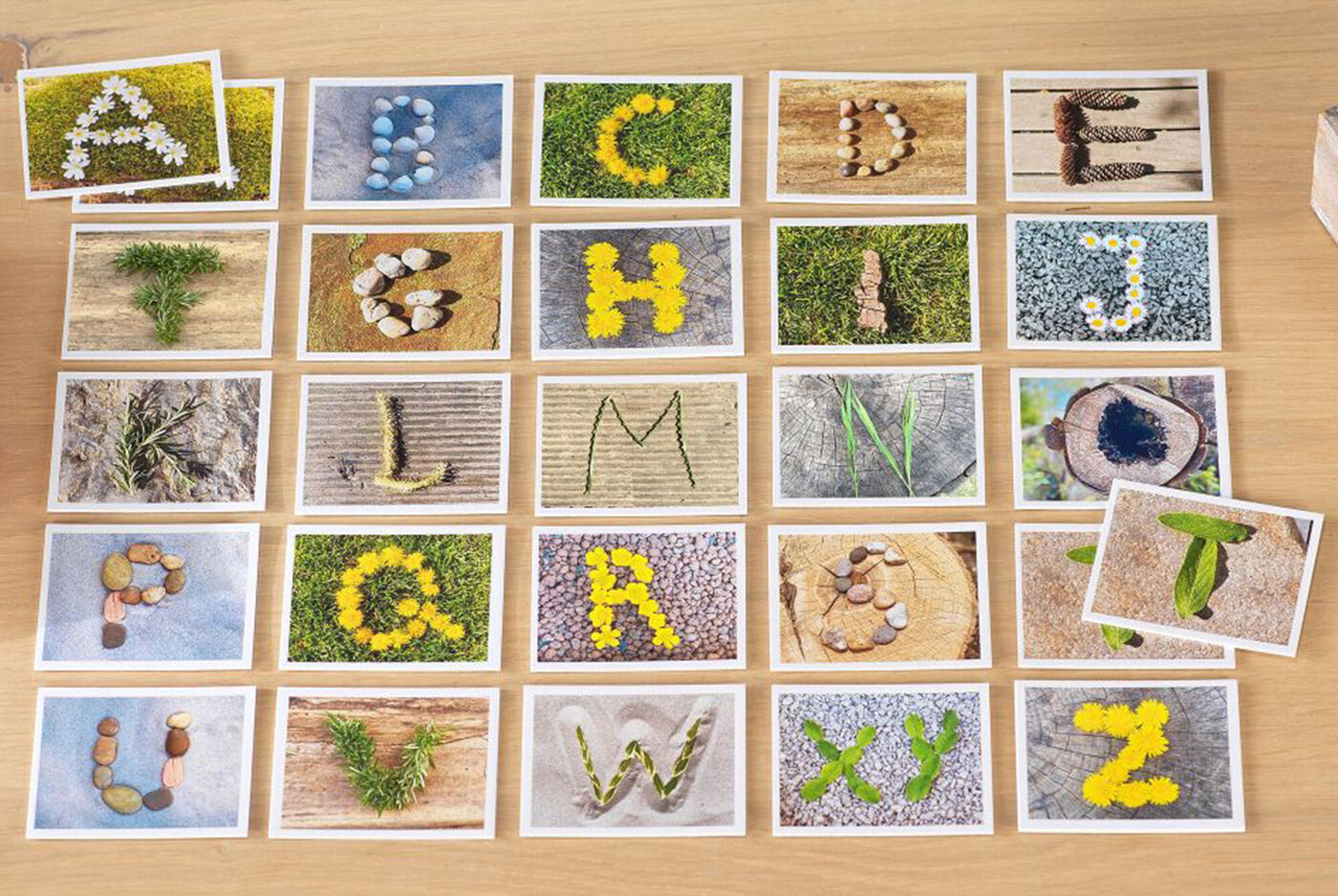 Ein Arrangement aus 26 Fotografien, die Buchstaben des Alphabets aus natürlichen Materialien wie Blumen und Steinen darstellen