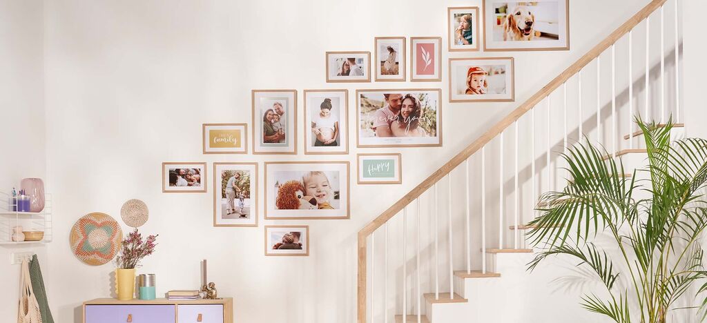 Bunte Fotowand mit verschiedenen gerahmten Bildern über Treppe im Wohnzimmer