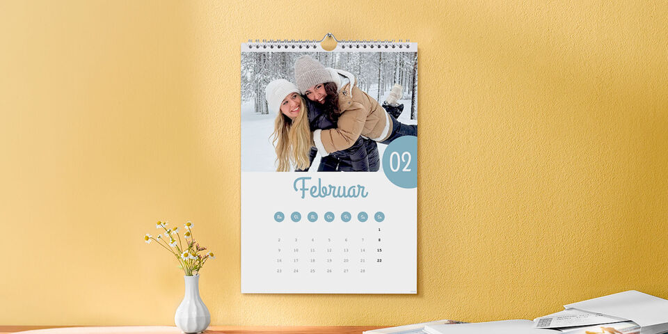 Ein CEWE Fotokalender mit einem winterlichen Bild für Februar hängt an einer Wand.