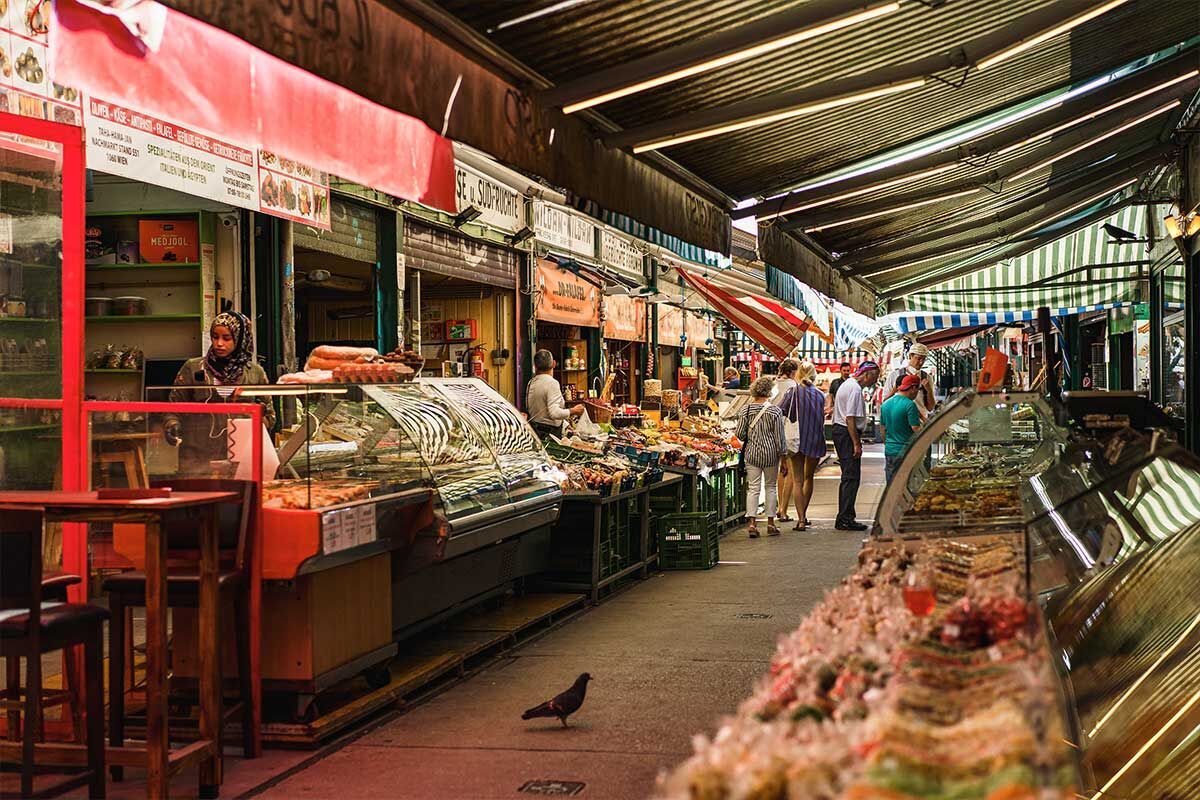Bunte Marktstände mit frischen Lebensmitteln und fröhlichen Menschen.