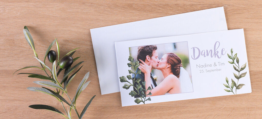 Elegante Dankeskarte für eine Hochzeit mit floralen Designs und einem romantischen Foto des Paares.