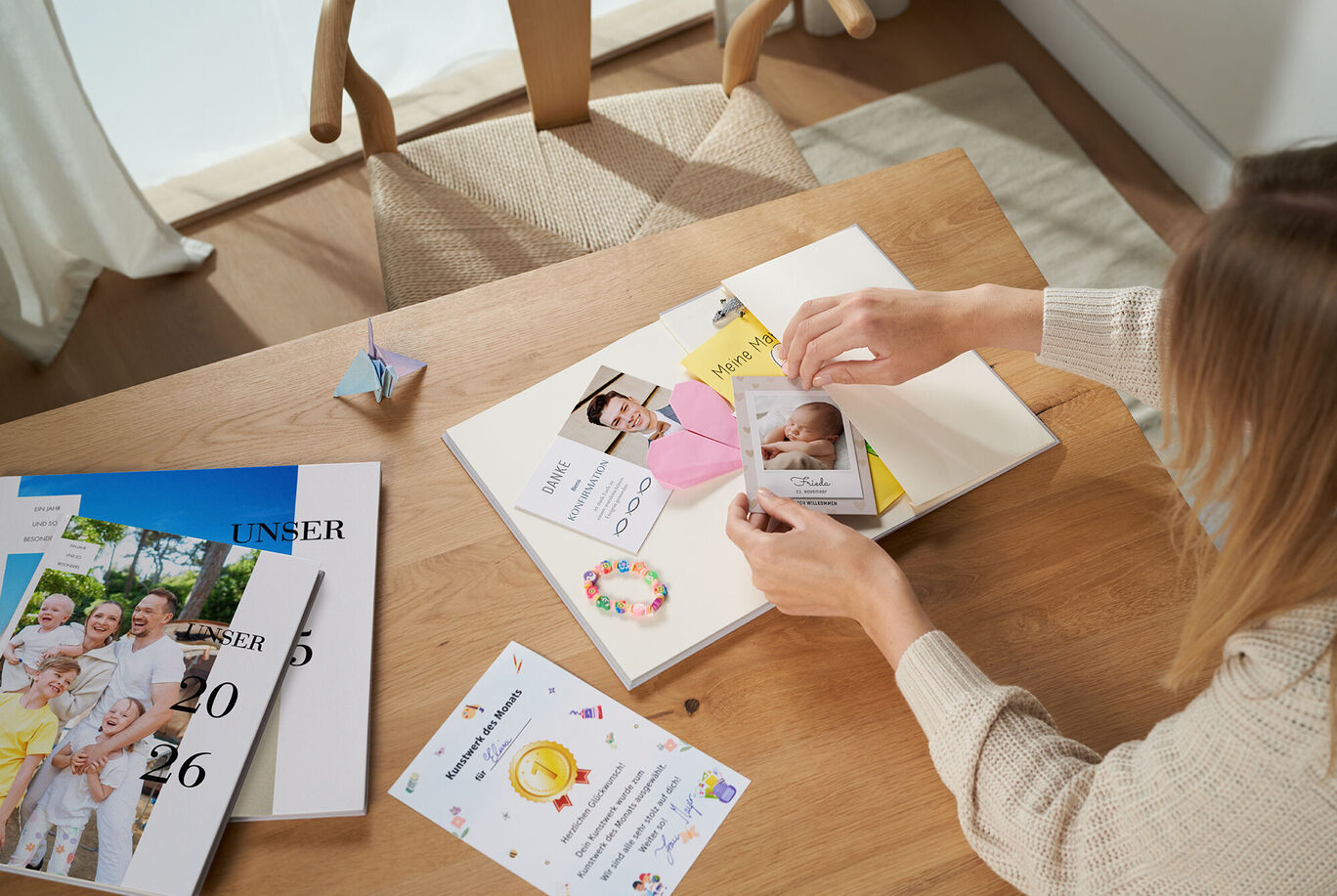 Eine Person gestaltet ein Fotobuch mit Erinnerungen auf einem Tisch.