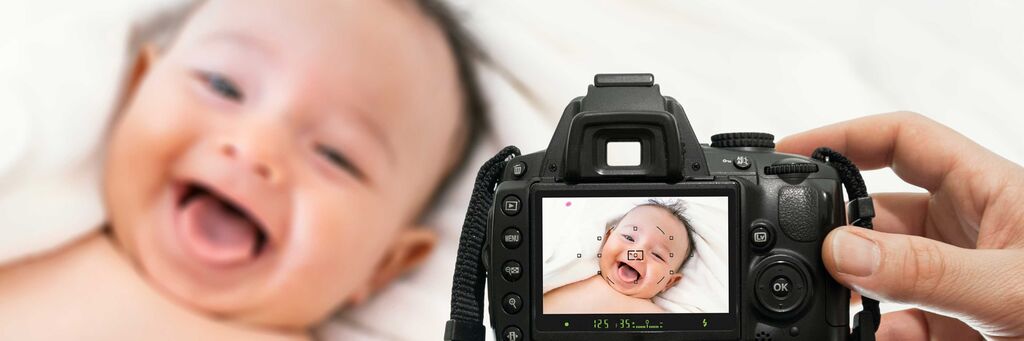 Fotograf hält Kamera und zeigt Bild auf dem Bildschirm