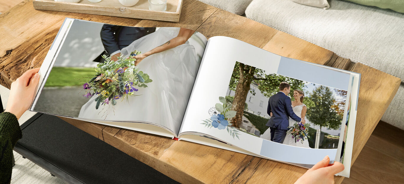 Offenes CEWE Fotobuch mit Hochzeitsfotos auf Holzoberfläche