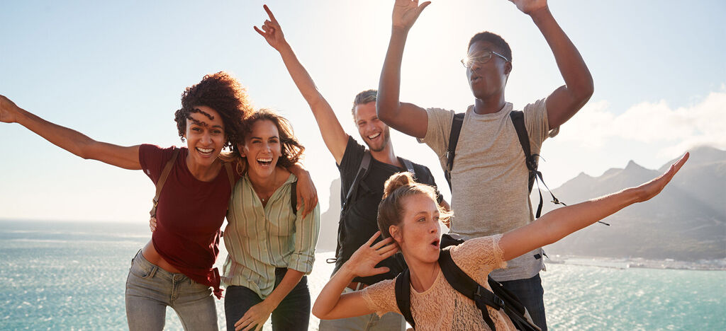 Gruppe von Freunden genießt einen sonnigen Tag am Meer mit Freude und Begeisterung