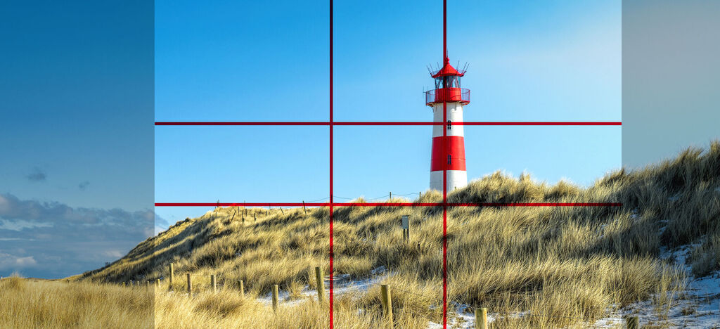 Leuchtturm steht inmitten von sandigen Dünen unter blauem Himmel