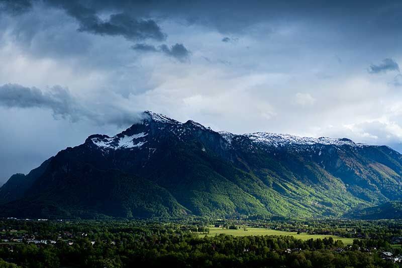 Eine majestätische Berglandschaft mit schneebedeckten Gipfeln und sattem Grün im Vordergrund.