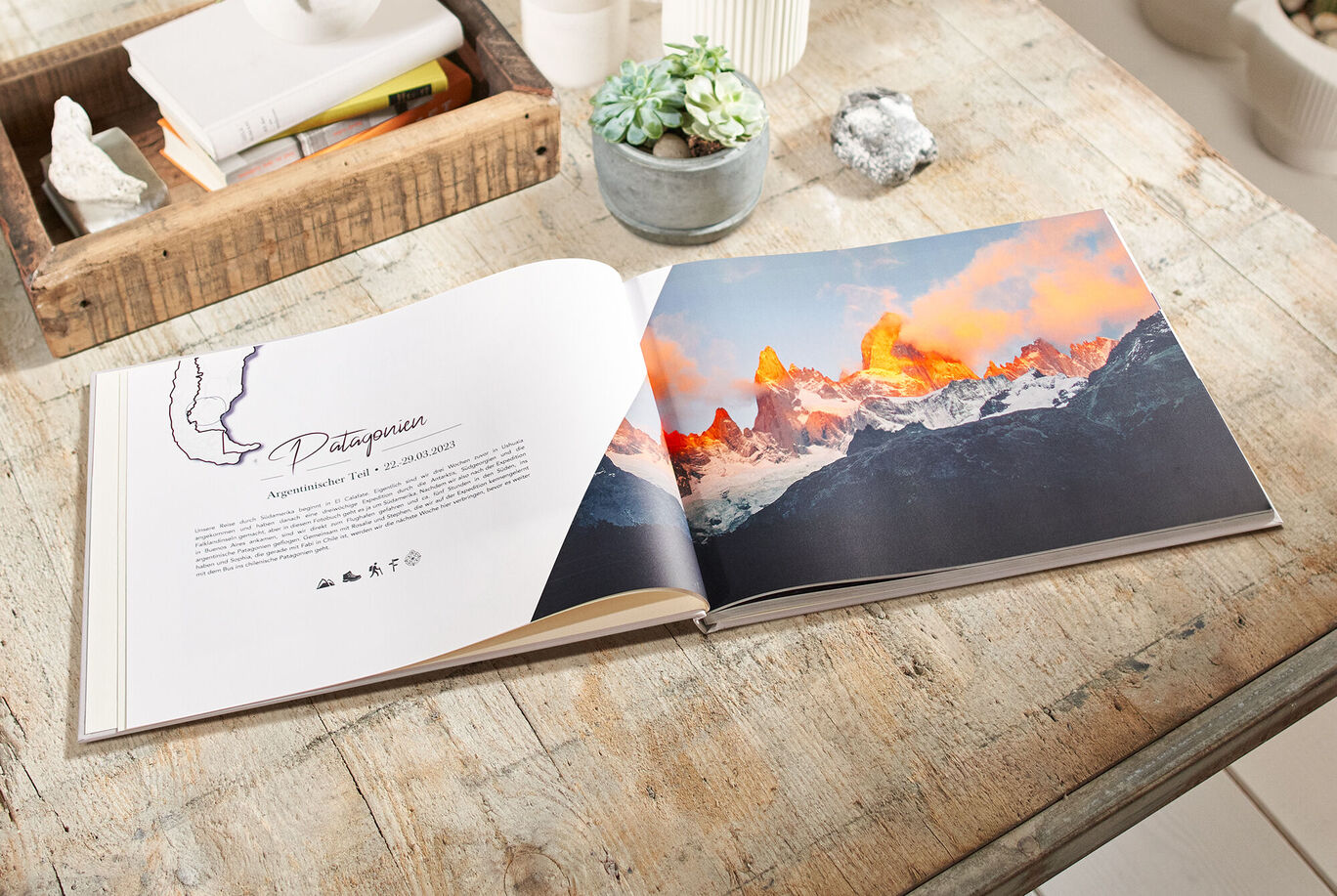 CEWE FOTOBUCH auf einem Tisch, zeigt beeindruckende Berglandschaft.