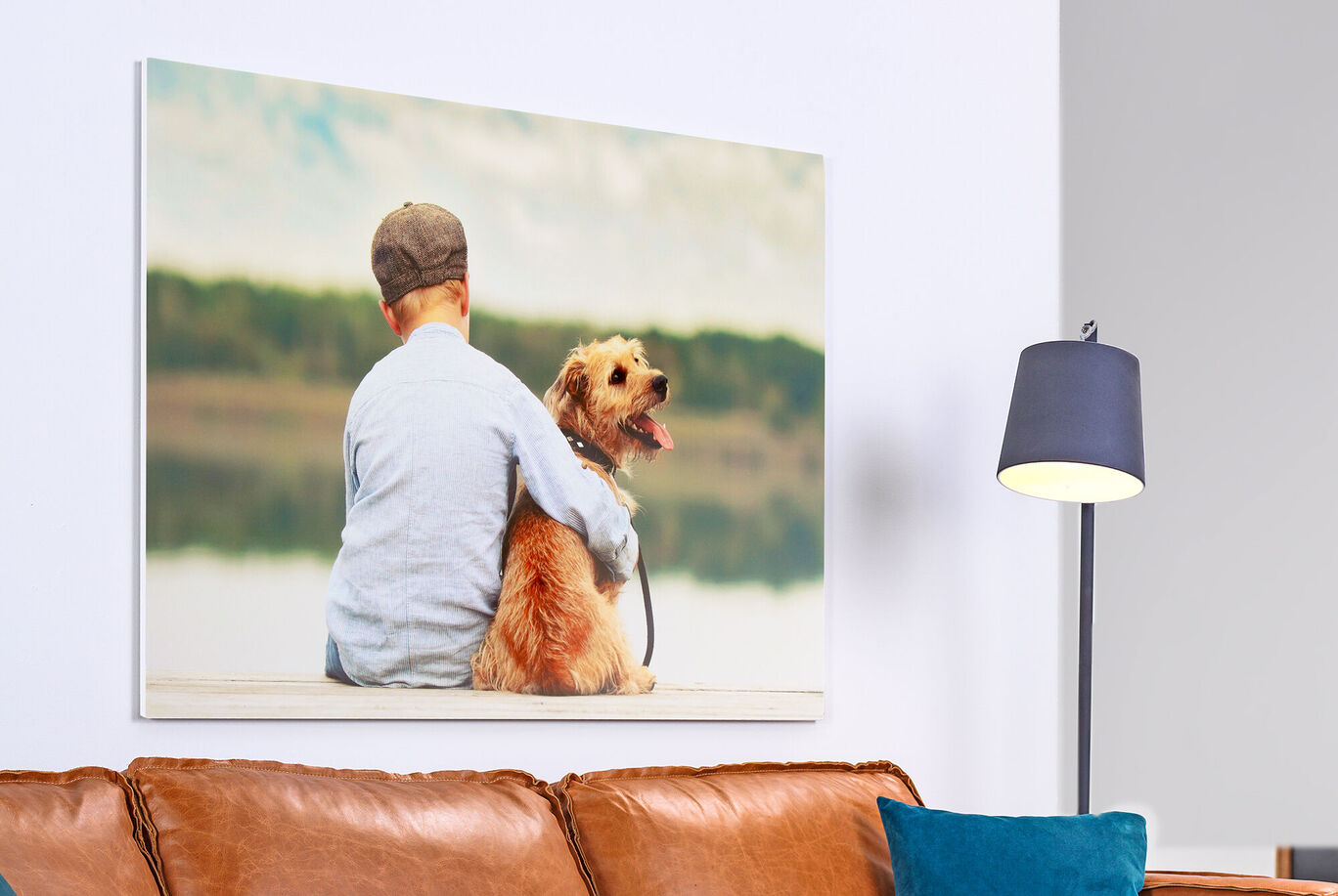 Ein Junge umarmt seinen Hund vor einem See. Sie sitzen auf einer Holzplattform und genießen zusammen den Ausblick.