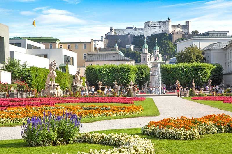 Bunte Blumenbeete in einem Garten mit Blick auf die Festung Hohensalzburg