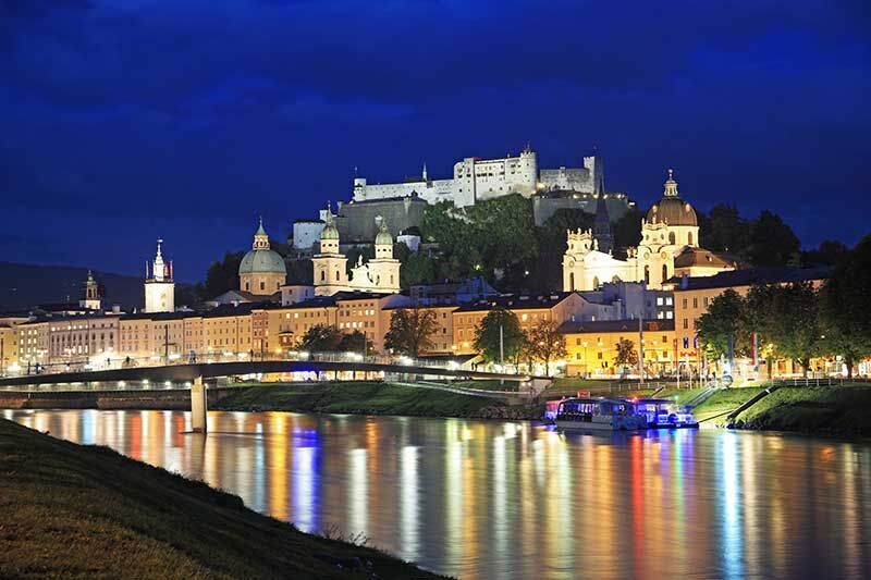 Abendlich beleuchtete Festung Hohensalzburg und Stadtansicht von Salzburg, Österreich.