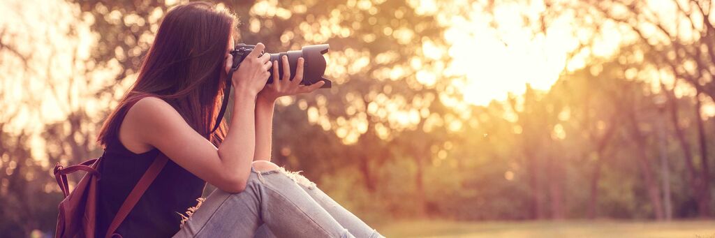 Eine junge Frau fotografiert eine schöne Landschaft im Sonnenuntergang