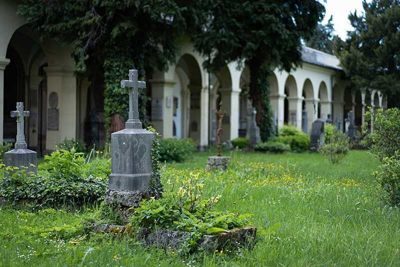 Begrünte Grabstätte mit Steinkreuz und Blumen