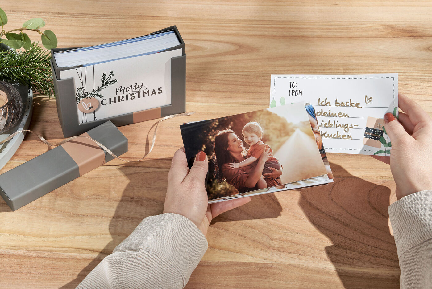 Zwei Menschen betrachten liebevolle Weihnachtsgrüße und Erinnerungsfotos in einem CEWE Fotobuch.