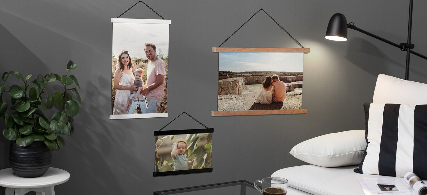 Drei Bilder in unterschiedlichen Rahmen hängen an einer grauen Wand. Sie zeigen glückliche Momente von Paaren und Familien.