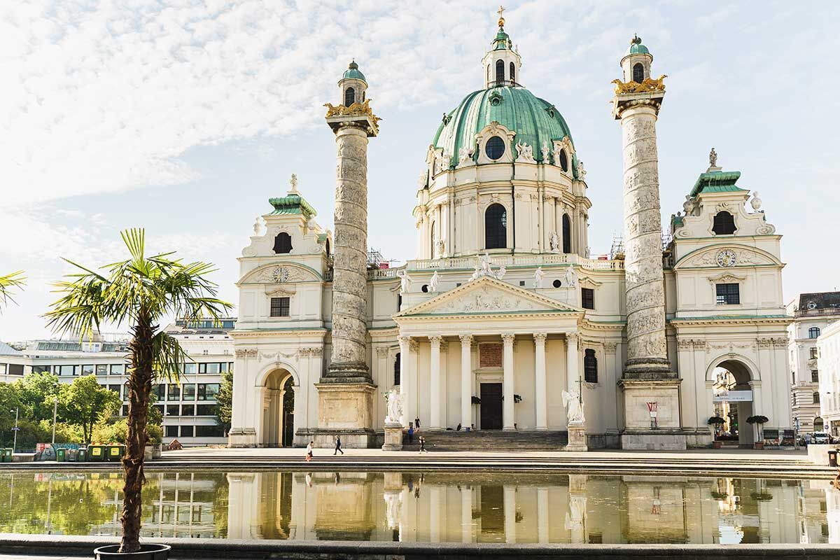 Die Karlskirche in Wien mit grüner Kuppel und Säulen im Vordergrund.