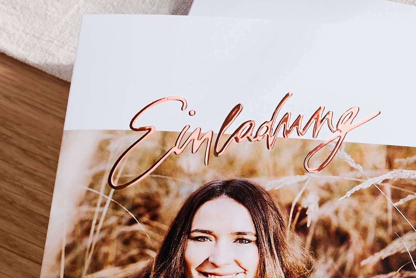 Grusskarte mit Rosegoldveredelung des Schriftzugs Einladung mit dem Foto einer lächelnden Frau