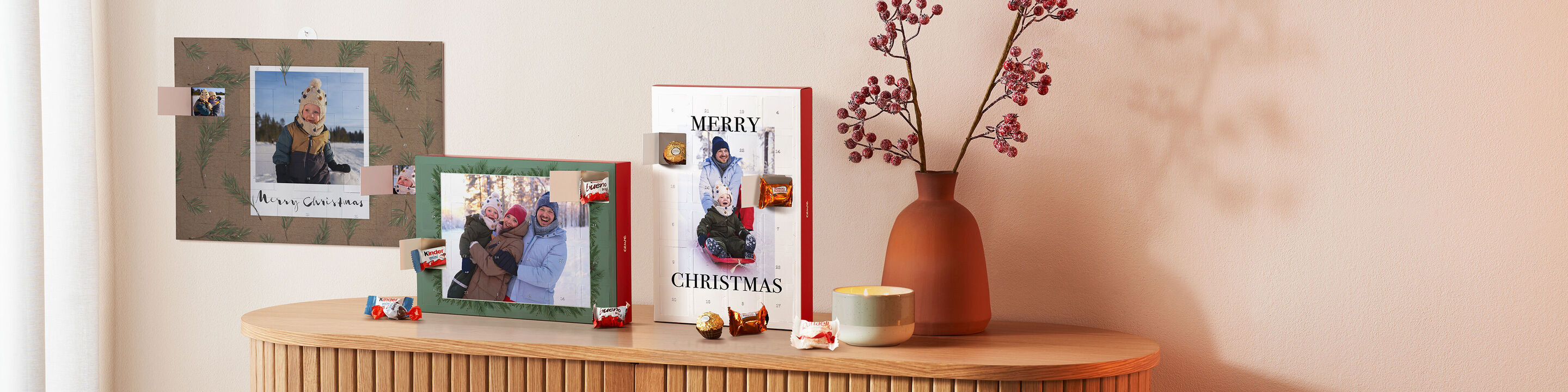 Drei Adventskalender von CEWE in Formate und Familienfotos auf einer weihnachtlichen geschmückten Kommode