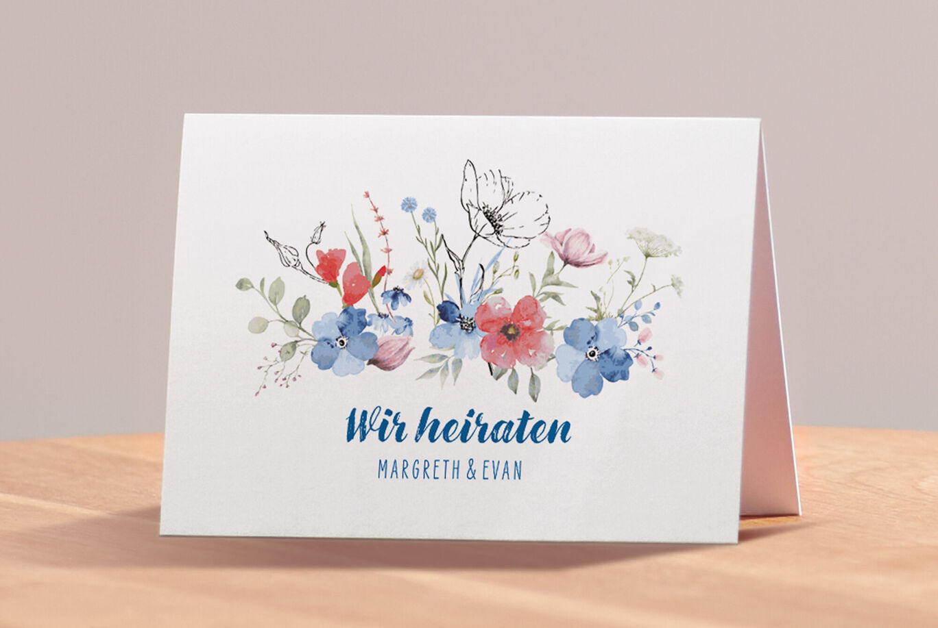 Eine liebevoll gestaltete Einladung zur Hochzeit mit bunten Blumen und einem Schmetterling. "Wir heiraten" steht in blauer Schrift.