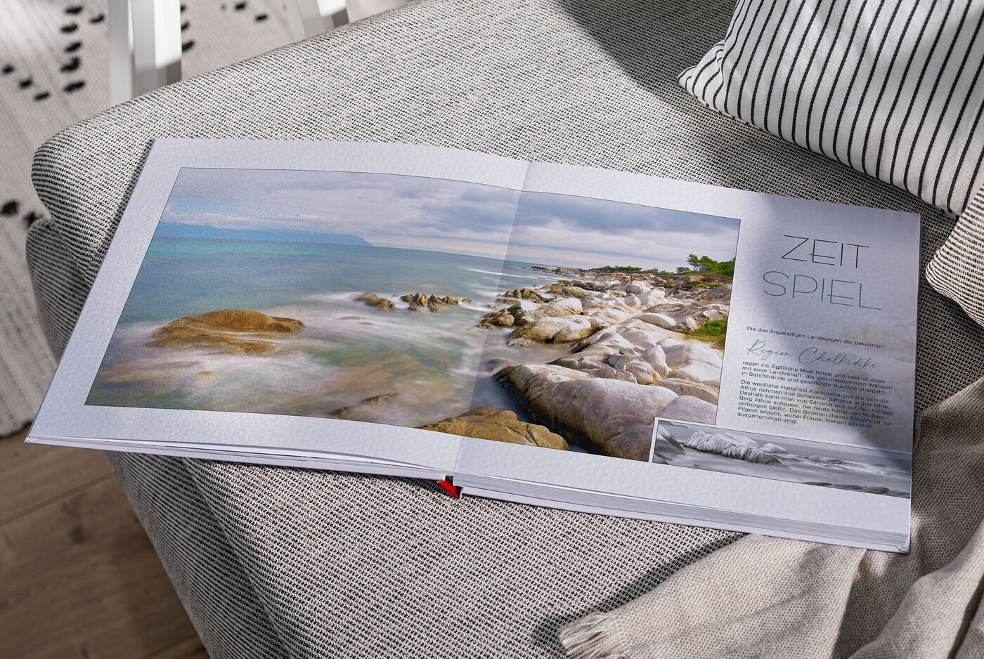 Ein geöffnetes CEWE Fotobuch auf einem gemütlichen Sofa, mit idyllischem Landschaftsbild auf der linken Seite und tekstlichem Inhalt auf der rechten Seite.