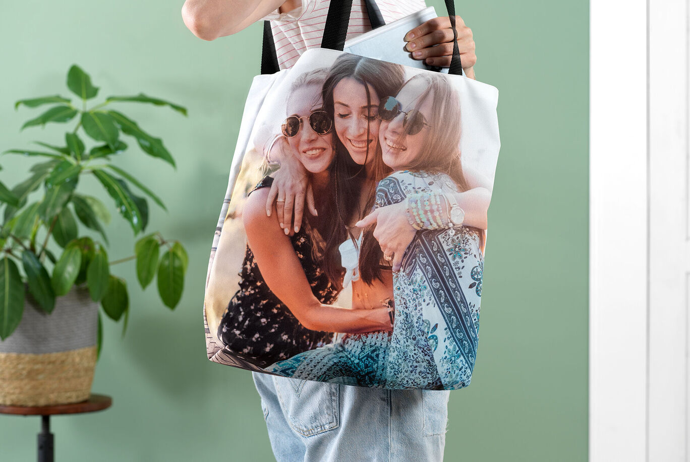 Eine Person hält eine Tasche mit einem Fotodruck von Freunden. Die Farben sind lebendig und die Atmosphäre ist freundlich.