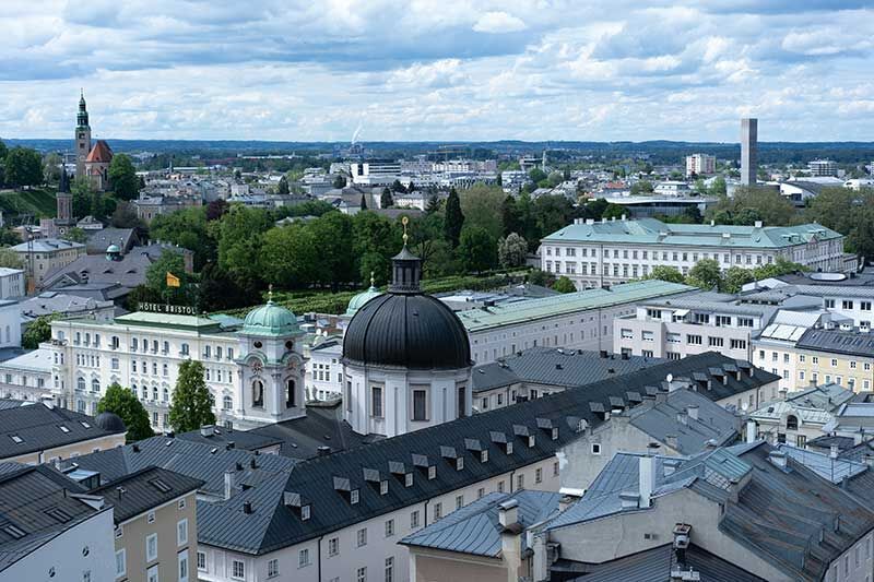Luftaufnahme von Salzburg mit grünen Parks und historischen Gebäuden unter bewölktem Himmel