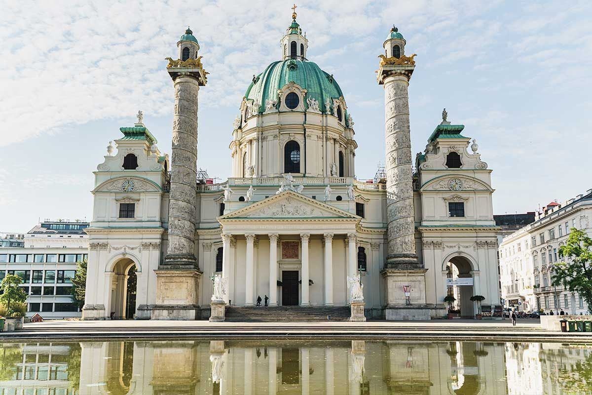 Die prächtige Karlskirche in Wien spiegelt sich im Wasser des Vorplatzes.