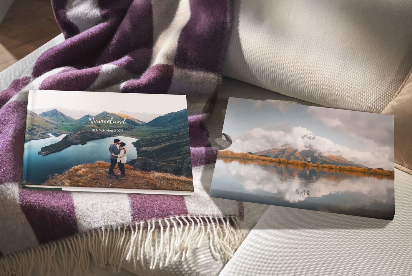 CEWE FOTOBUCH und Fotobuch-Schuber auf einer Couch mit Decke