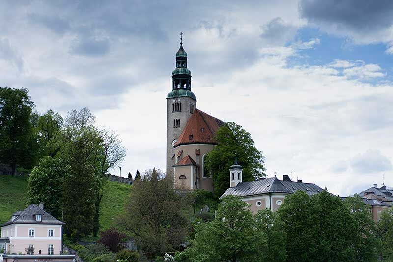Eine schöne Kirche auf einem Hügel, umgeben von grünen Bäumen und Häusern
