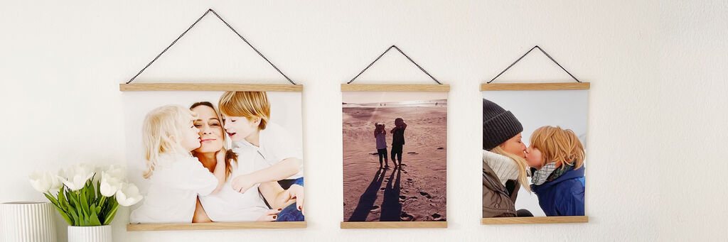 Zwei Fotodrucke hängen an der Wand, sie zeigen glückliche Momente zwischen Kindern und Erwachsenen.