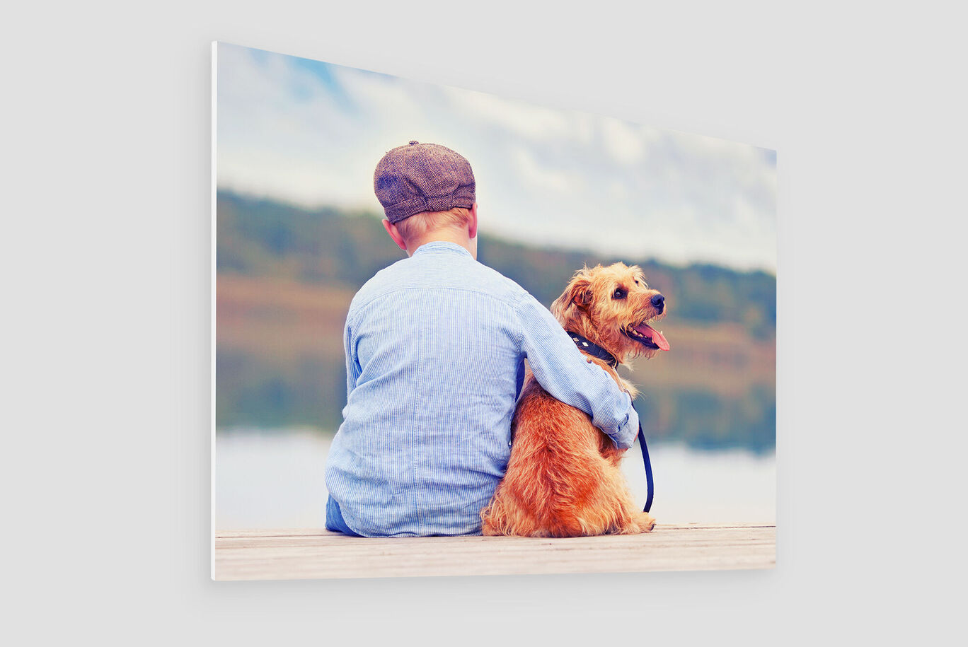 Ein Junge sitzt mit einem Hund am Wasser und schaut zusammen in die Ferne