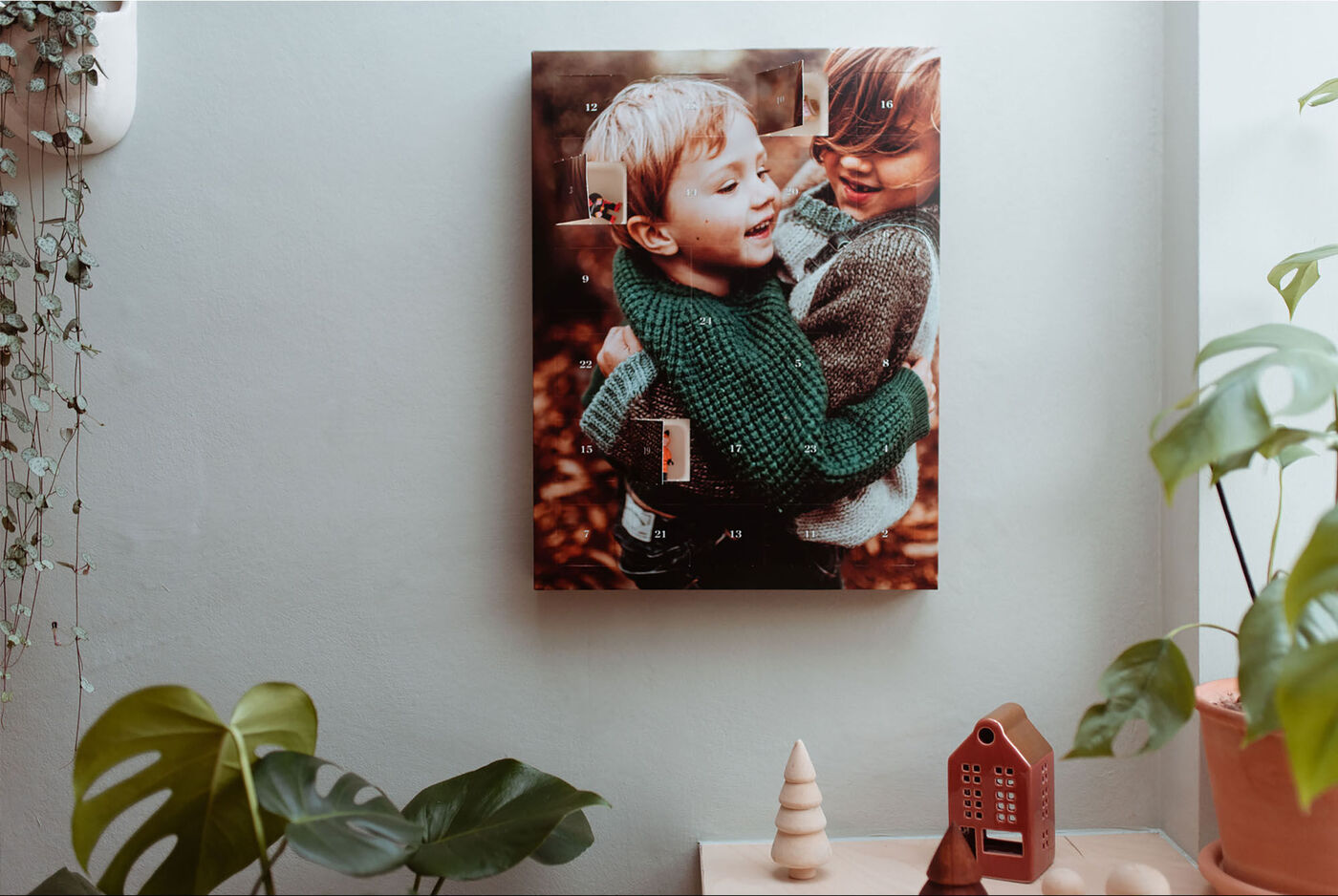 Zwei Kinder umarmen sich herzlich vor einer Wand mit Pflanzen.