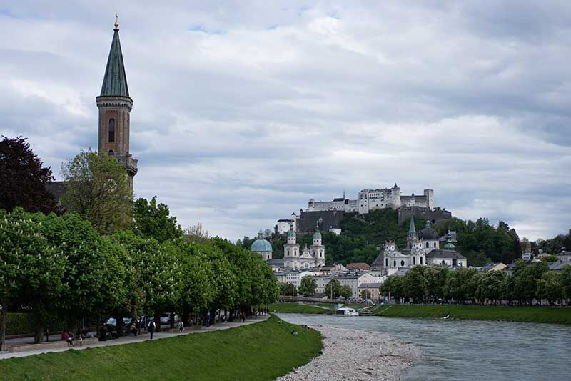 Aussicht auf die Salzach mit Bäumen und einer Altstadt im Hintergrund