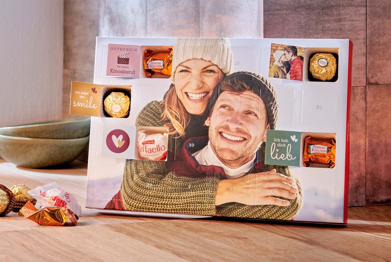 CEWE Adventskalender gefüllt mit Pralinen von Ferrero und persönlichen Botschaften in den Türchen mit dem Foto eines glücklichen Paares.