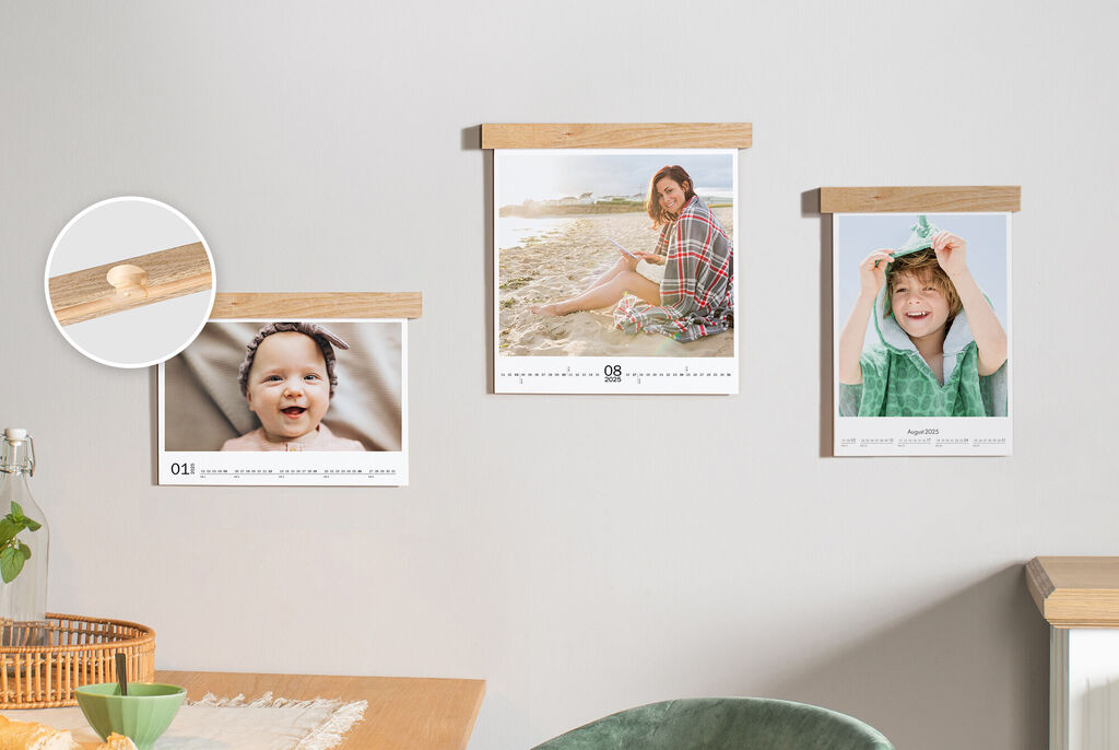 Drei Fotokalender mit Holzelementen an der Wand, ein Bild zeigt eine Person am Strand, ein weiteres ein Kind mit einem Handtuch.